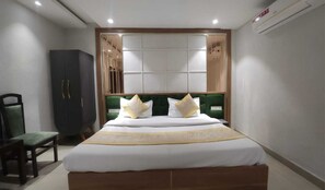 Ein Hotelzimmer mit einem großen Bett, einem grünen, gepolsterten Kopfteil und einem Kleiderschrank.