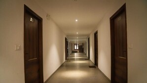 Un lungo corridoio stretto con porte in legno su entrambi i lati, che conduce a una stanza in fondo.