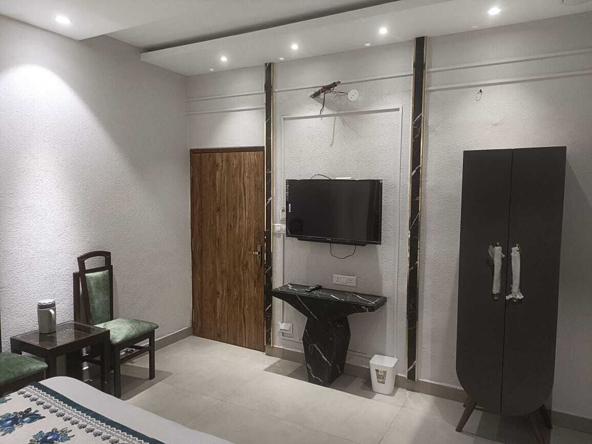 Ein Schlafzimmer mit einem Bett, einer Holztür, einem schwarzen Schrank, einem an der Wand montierten Fernseher und einem kleinen Tisch mit Stuhl.