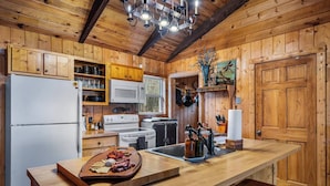 A wooden cabin kitchen with a central island, wooden cabinets, a microwave, stove, and a sink. - Lake Lahusage Front l Private Dock, Game Room (Mentone)