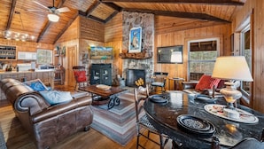 A rustic cabin interior with a fireplace, wooden walls, a dining area, and a kitchen. - Lake Lahusage Front l Private Dock, Game Room (Mentone)