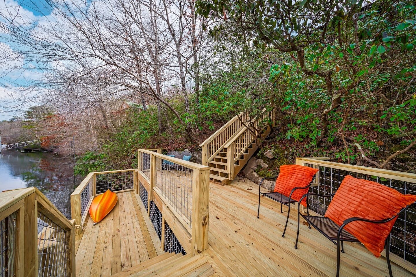 A wooden deck with a slide, chairs, and a staircase leading to a higher level.