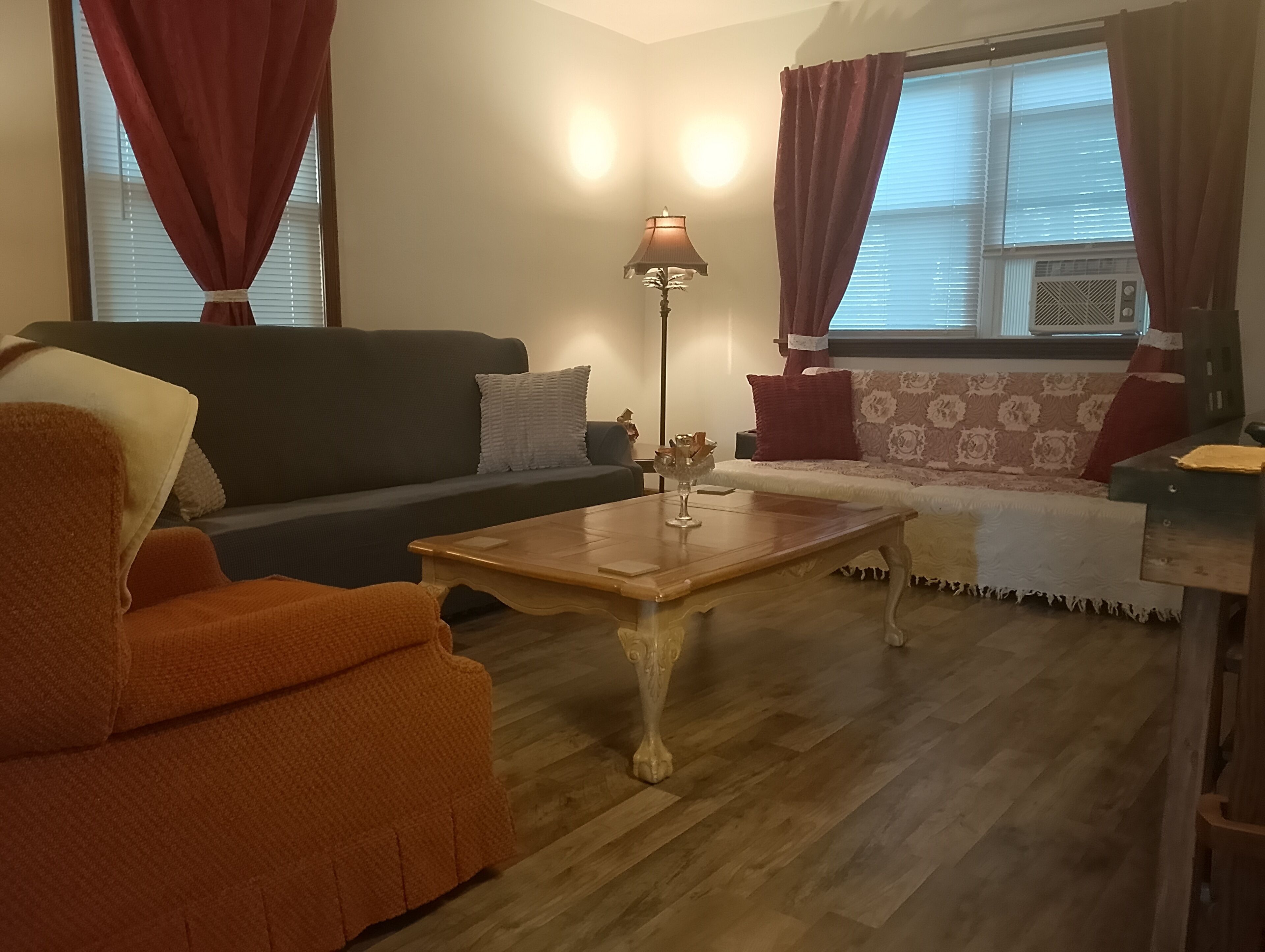 Un salon comprenant un canapé, un fauteuil, une table basse et une lampe.