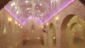 A salt cave with arched ceilings, illuminated by purple lights, and equipped with fans and heaters. - Gazrashek Siwa Eco Lodge (Siwa)