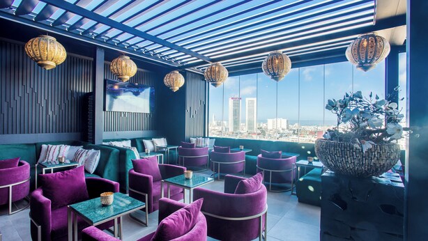 A rooftop lounge with purple seating, a large decorative bowl, and hanging lanterns. - W-Aldorf (Casablanca)