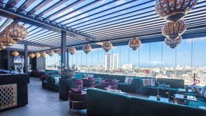 A rooftop lounge with green sofas, purple chairs, and hanging lanterns. - W-Aldorf (Casablanca)
