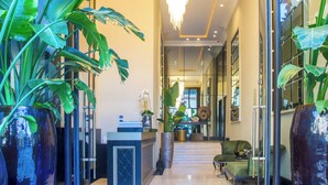 A hotel lobby with a reception desk, a chandelier, and large potted plants. - W-Aldorf (Casablanca)