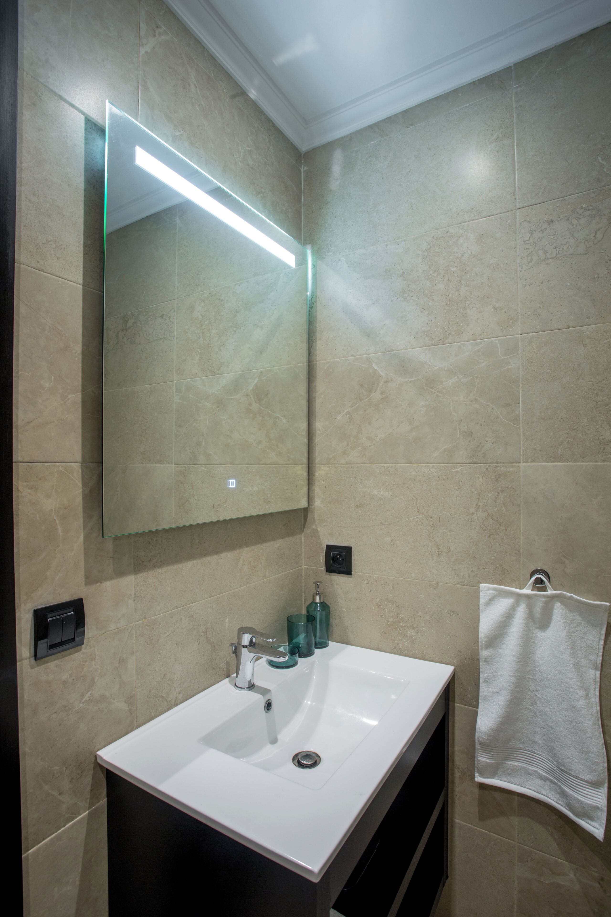 A bathroom with a white sink, a mirror, and a towel rack.