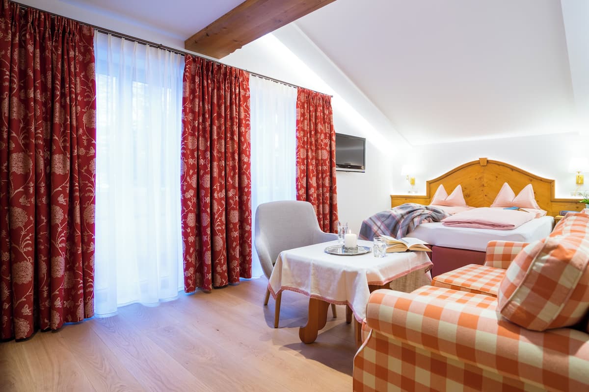 A hotel room with a bed, a sofa, a table with a candle, and curtains.