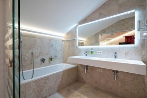 A modern bathroom with a glass-enclosed shower, a white sink, and a large mirror. - Hotel Lech (Lech am Arlberg)