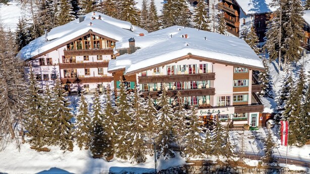 Un hôtel à plusieurs étages, doté de balcons et entouré d’arbres couverts de neige.