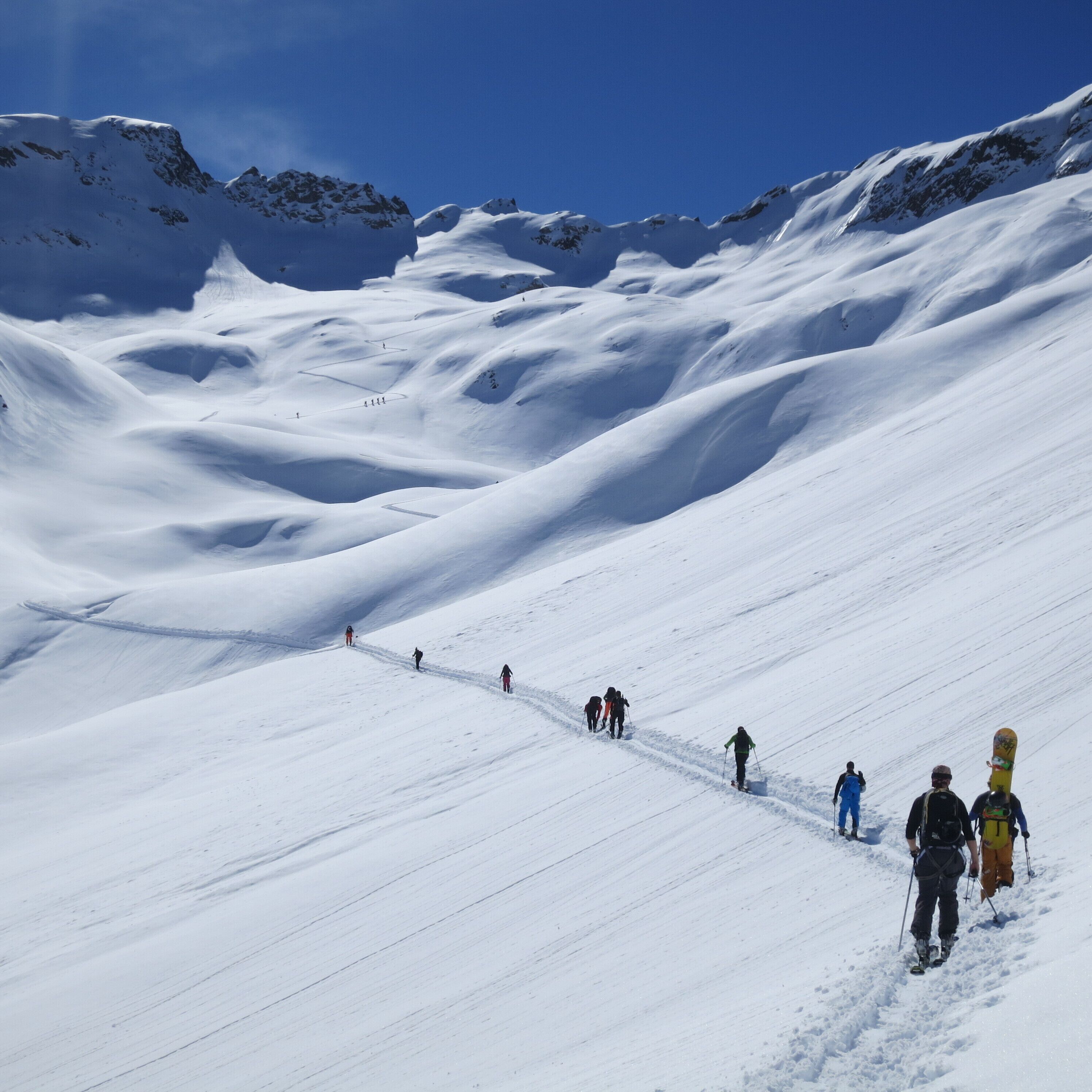 A snowy mountain slope with skiers descending.