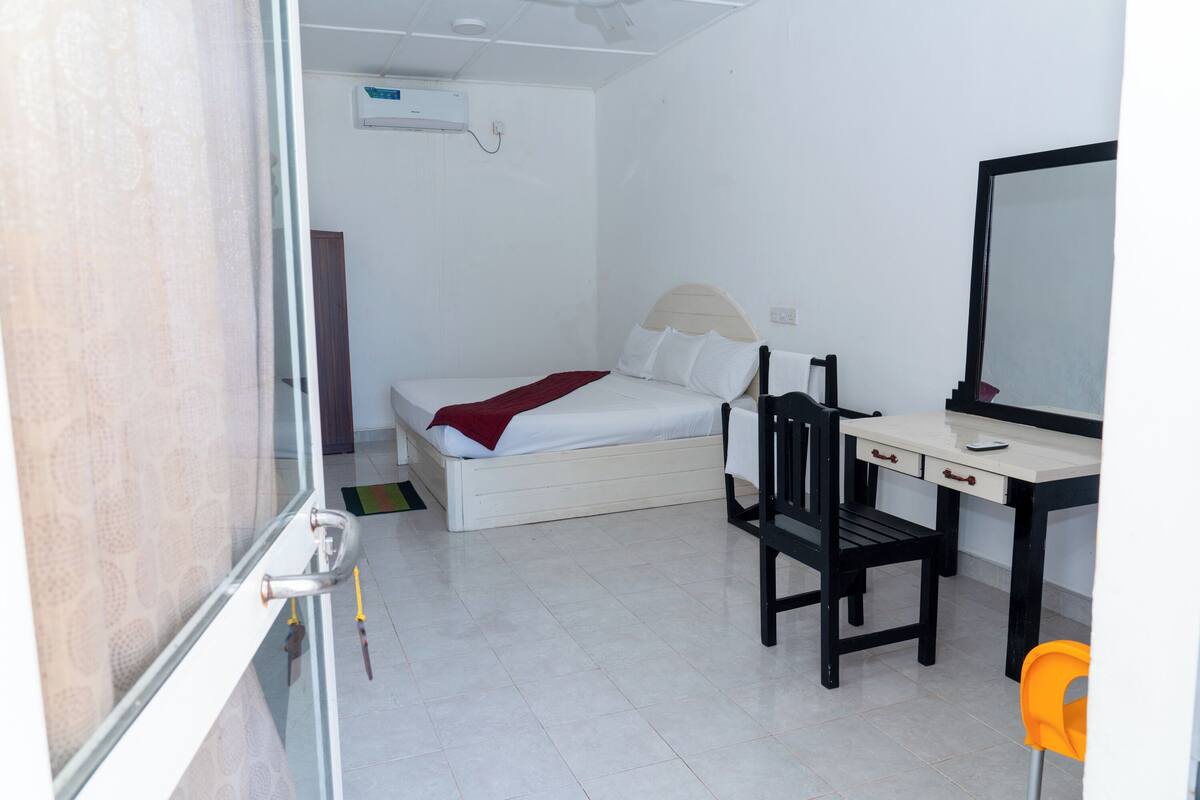 A bedroom with a bed, a desk, and a chair.