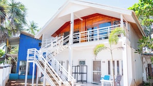 A two-story house with a balcony, a staircase, and a small garden area.