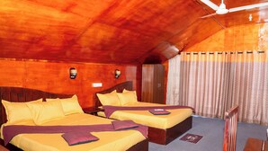 A room with two beds, wooden ceiling, and a ceiling fan.
