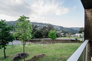 Un espacio cubierto de césped con árboles y una valla, con vistas a un paisaje ondulado.