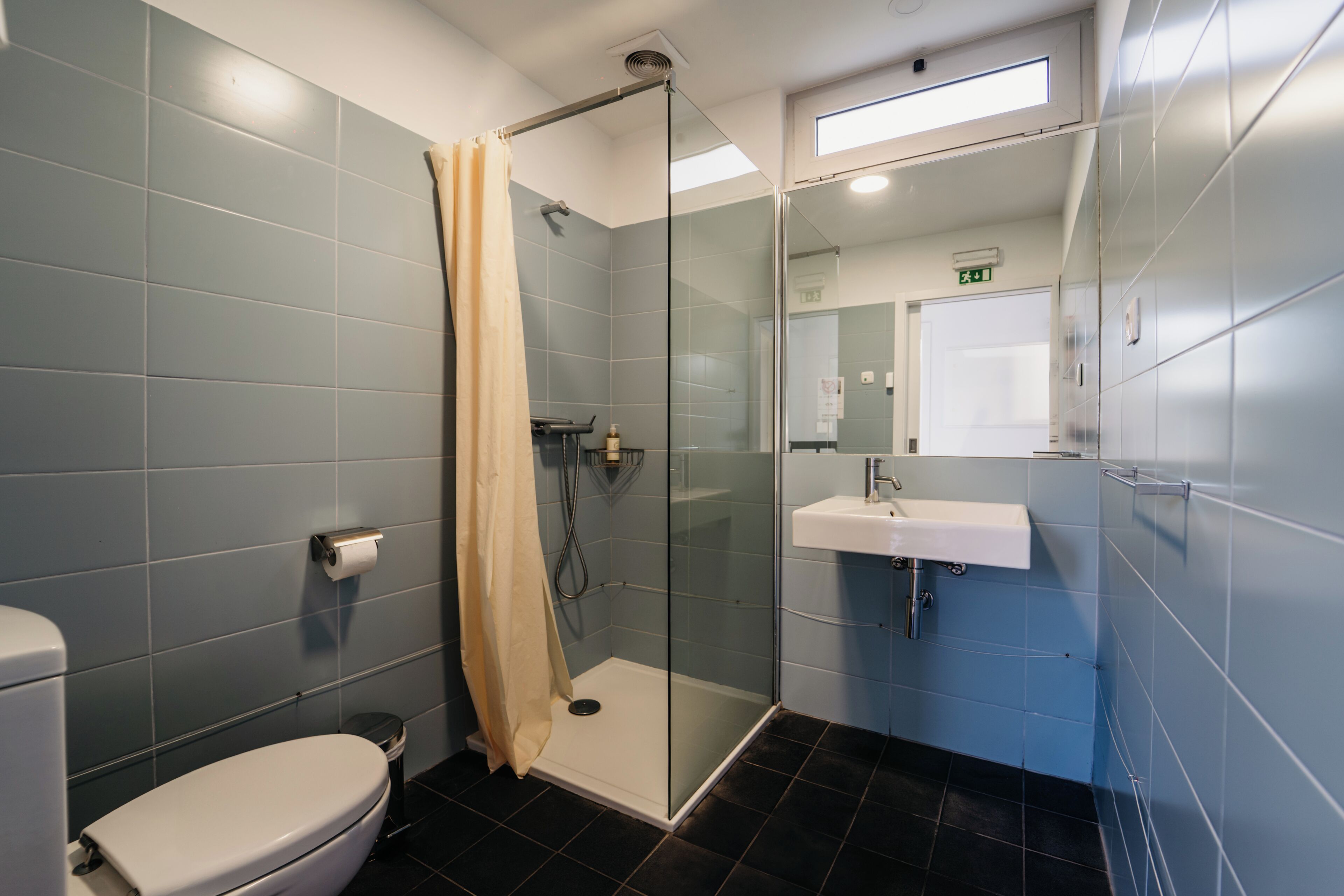 Un baño moderno con ducha de vidrio, lavamanos blanco y retrete.