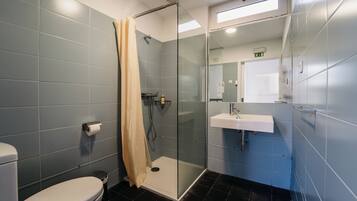 Un baño moderno con ducha de vidrio, lavamanos blanco y retrete.