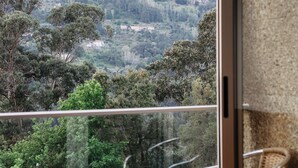 A balcony with a view of a hilly landscape, a wicker chair, and a small table. - Welcome Douro (Cinfães)