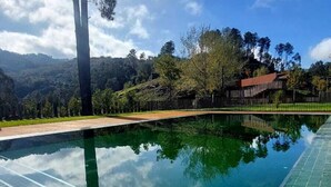 A swimming pool with a clear view of the surrounding landscape, including trees and a distant building. - Welcome Douro (Cinfães)
