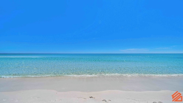 Ein Strand mit klarem türkisblauem Wasser und einem sandigen Ufer.