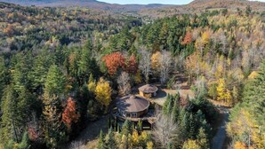 Una cabaña apartada rodeada de un bosque frondoso con vistas despejadas de las colinas circundantes.