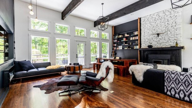 A spacious living room with a fireplace, large windows, and a modern design.