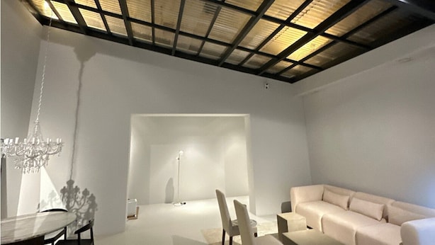 Un interior moderno con techos altos, una zona de comedor con candelabro, un sofá y un diseño minimalista.