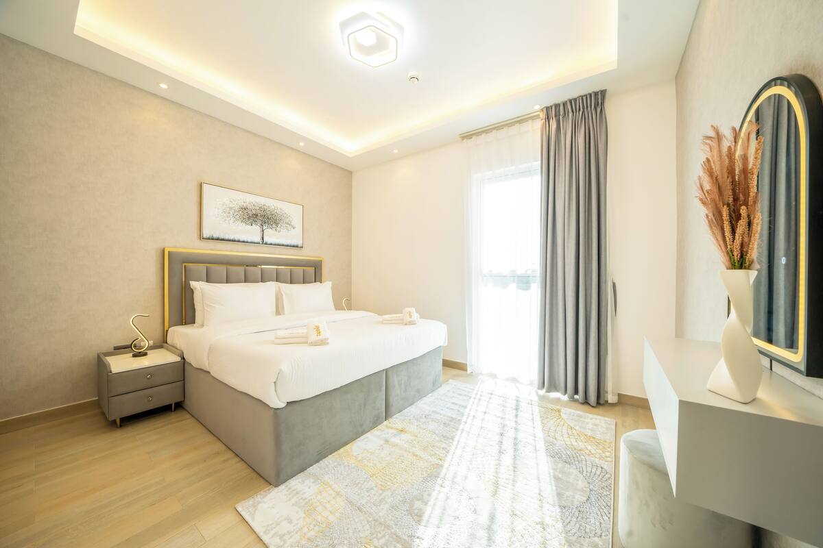 Une chambre moderne avec un lit, une table de chevet et une grande fenêtre avec des rideaux.