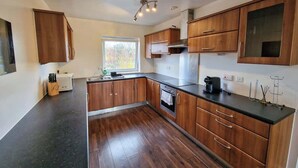 Une cuisine moderne avec des meubles en bois, un plan de travail noir et une fenêtre qui laisse entrer la lumière naturelle.