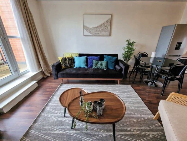 Una sala de estar con sofá, mesa de centro y comedor con sillas.