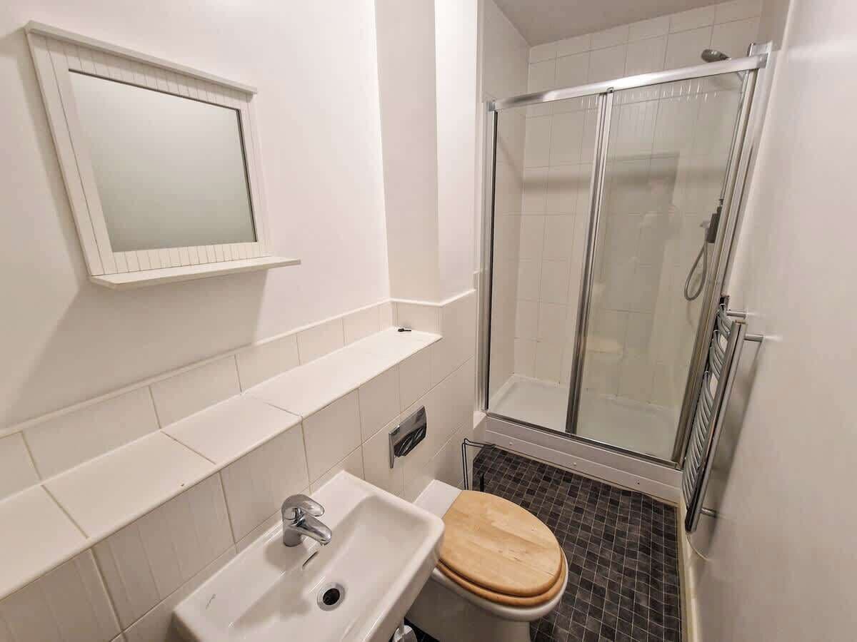 Et badeværelse med vask, spejl, toilet og brusekabine i glas.