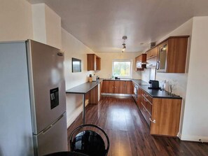 Una cocina moderna con gabinetes de madera, electrodomésticos de acero inoxidable y un amplio ventanal.