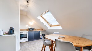 A modern kitchen with a skylight, a dining area with a wooden table and chairs, and a compact layout.