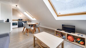 A modern kitchen with a dining area, a TV, and a basketball.