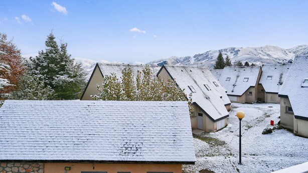A snow-covered village with traditional houses and a mountain backdrop.