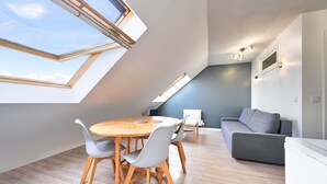 A modern loft apartment with a dining area, a sofa, and skylights.