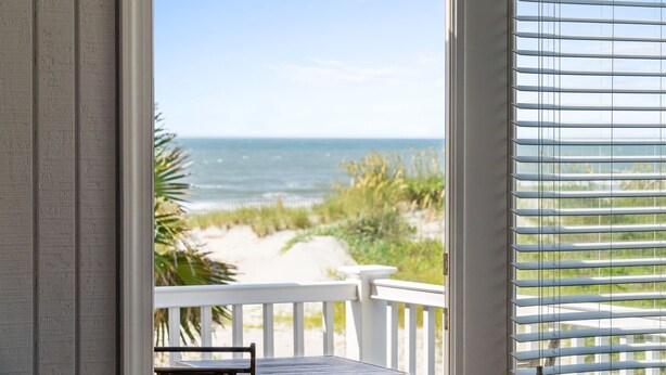 Ein Balkon mit Blick auf Strand und Meer.