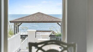 Blick vom Balkon auf einen Strand mit einem Pavillon.
