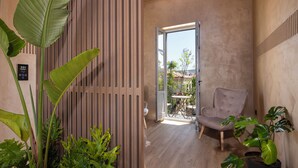 A modern interior with a wooden partition, a grey armchair, and potted plants. - Nearchou Boutique Hotel (Chania)