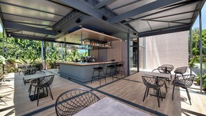 An outdoor dining area with a bar, tables, and chairs. - Nearchou Boutique Hotel (Chania)