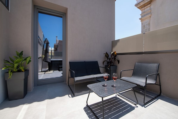 A balcony with a sofa, two chairs, a small table, and two wine glasses. - Nearchou Boutique Hotel (Chania)