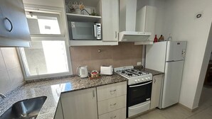 A compact kitchen with a gas stove, microwave, toaster, and a refrigerator.