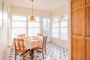 A dining area with a round table, four chairs, and a hanging light fixture.