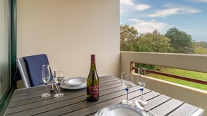 A balcony table with a bottle of wine, two glasses, and a plate. - Ferienwohnung in St. Peter-ording (St. Peter-Ording)