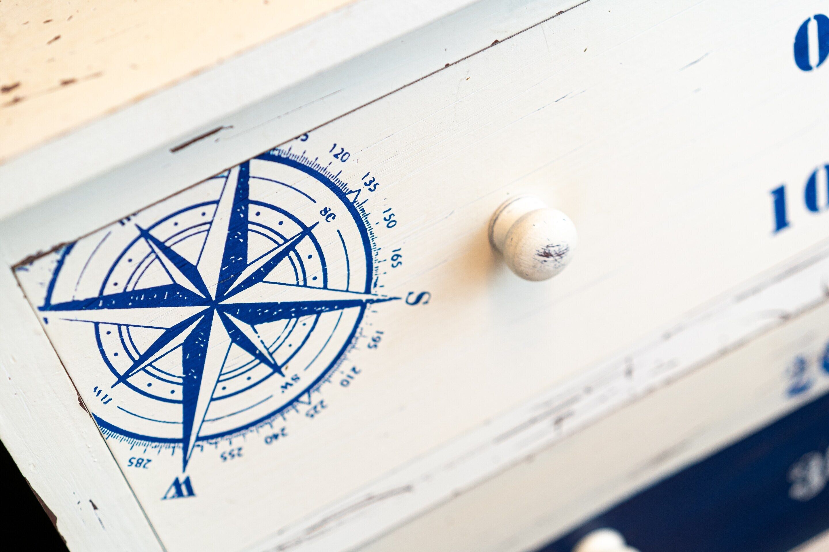A compass rose on a wooden surface with a white knob.