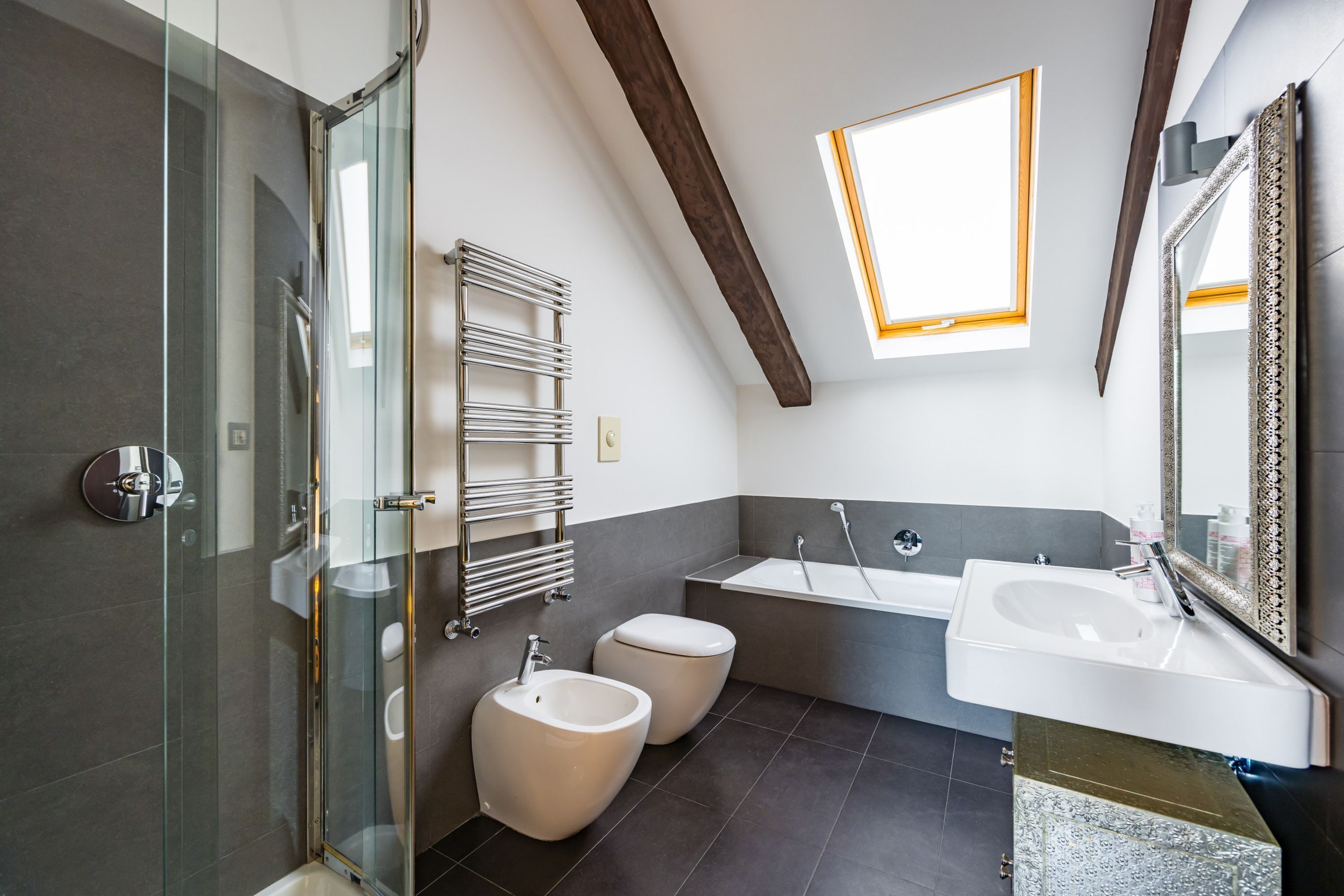 A modern bathroom with a glass shower enclosure, a freestanding bathtub, and a large mirror.