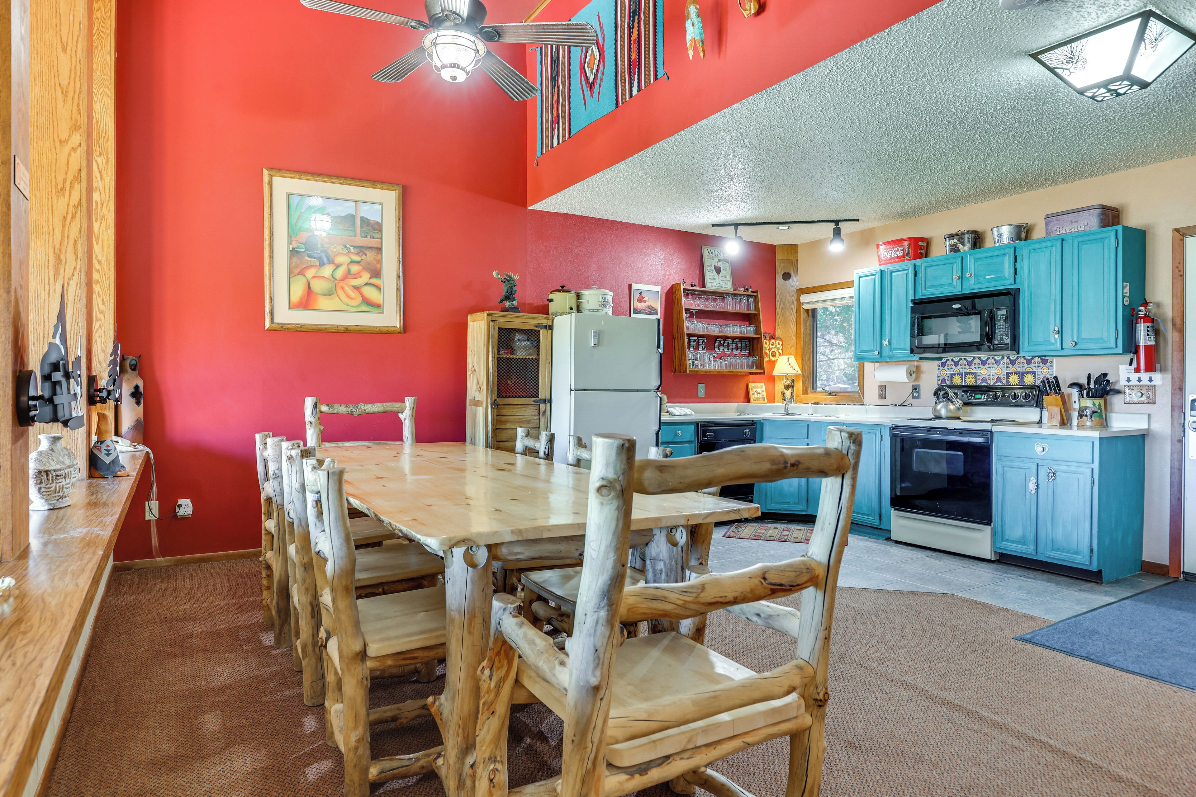 Un comedor con una mesa y sillas de madera, un refrigerador y un microondas en la cocina.