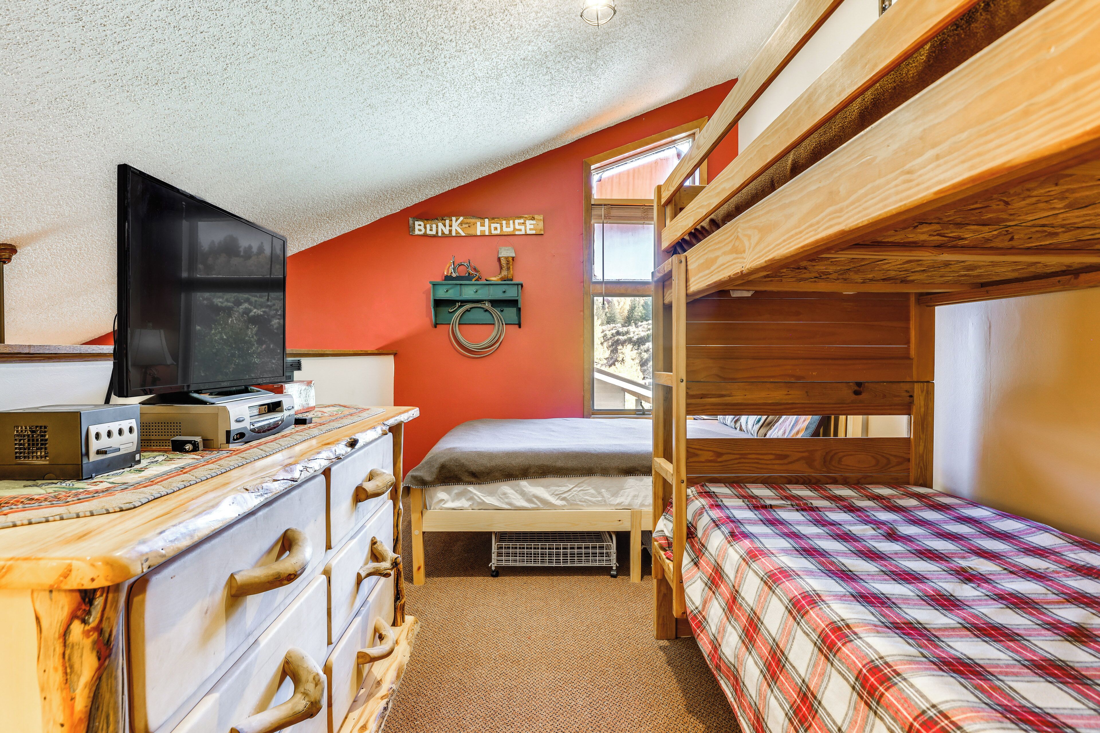 Ein Schlafraum mit Etagenbetten, einem Fernseher, einem Schminktisch und einem Schild mit der Aufschrift 'Bunk House'.