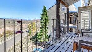 A wooden deck with a metal railing, overlooking a road and distant landscape. - Walk to Ski Lift & Hiking: Granby Ranch Condo! (Granby)